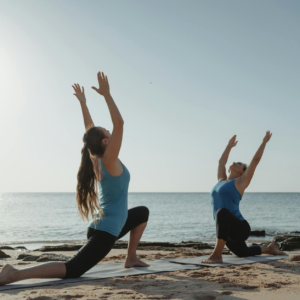 Dos mujeres practicando yoga privado en Altea junto al mar en pose de guerrero mirándose la una a la otra.