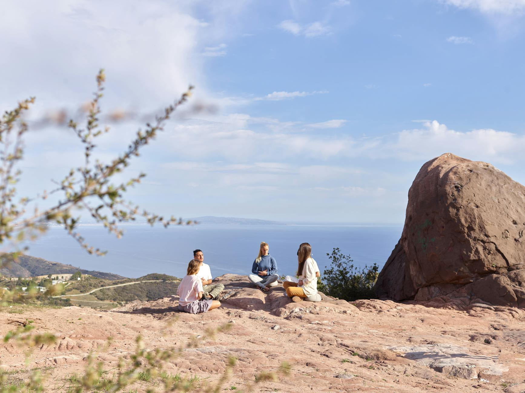 Grupo internacional practicando yoga al aire libre en un terreno rocoso con el horizonte del mar Mediterráneo - Día de Retiro de Yoga en Altea, Costa Blanca